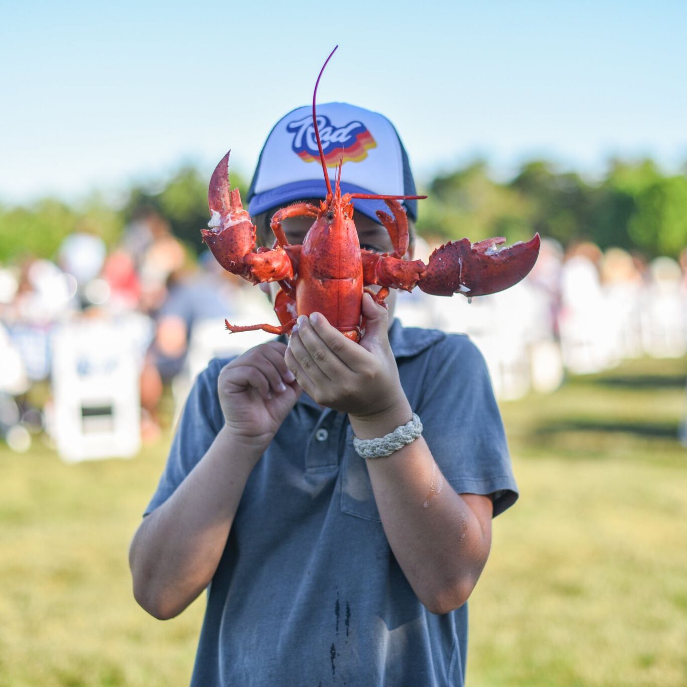 A boy with a lobster in front of his face
